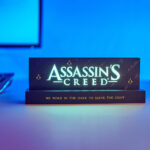Lampe avec le logo du jeu vidéo Assassin's Creed, de la marque Neamedia Icons, allumée, en situation sur un bureau