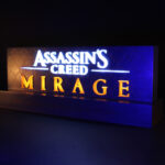 Lampe avec le logo du jeu vidéo Assassin's Creed Mirage, allumée, vue de trois quart, dans le noir