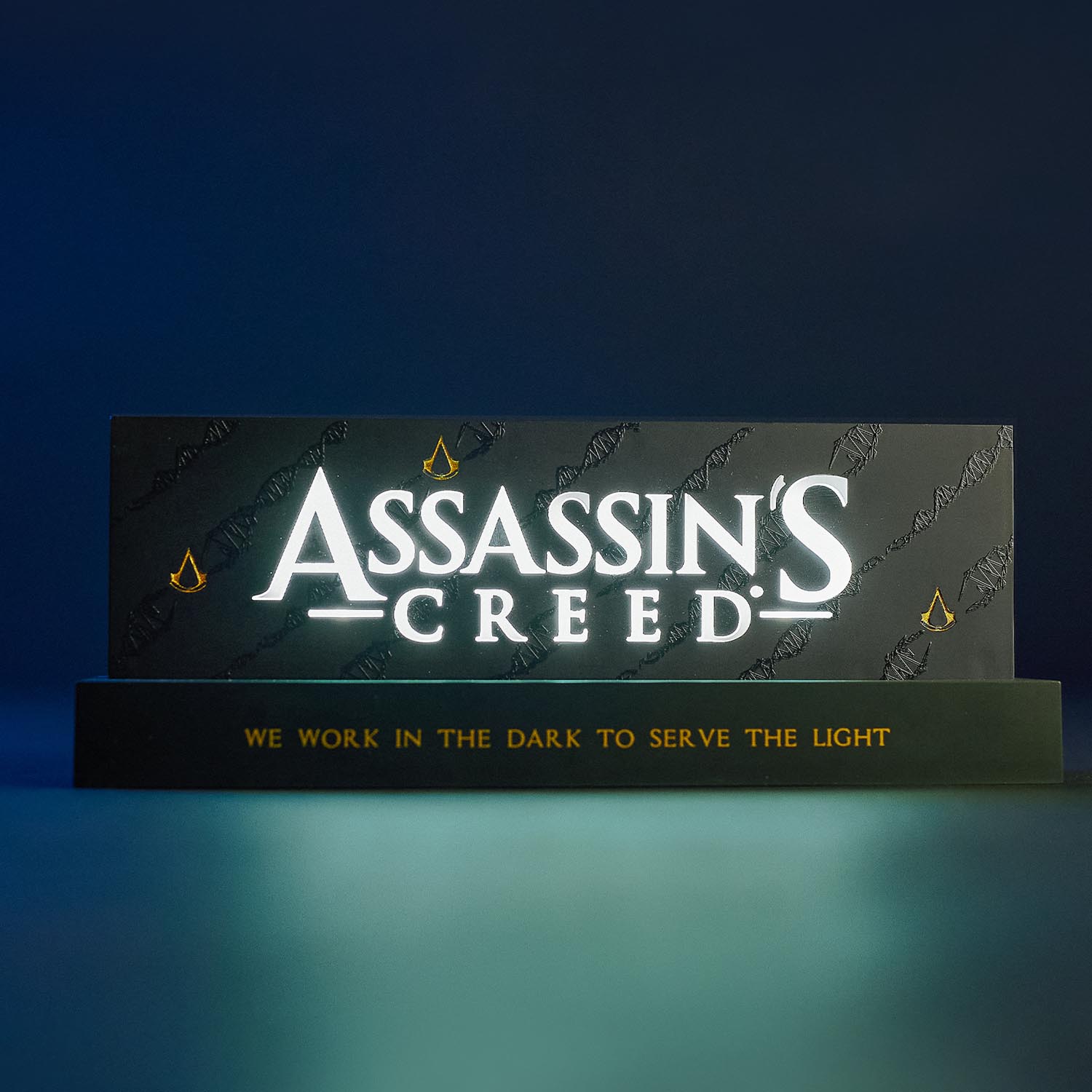 Lampe avec le logo du jeu vidéo Assassin's Creed, de la marque Neamedia Icons, vue de face, allumée dans un environnement sombre