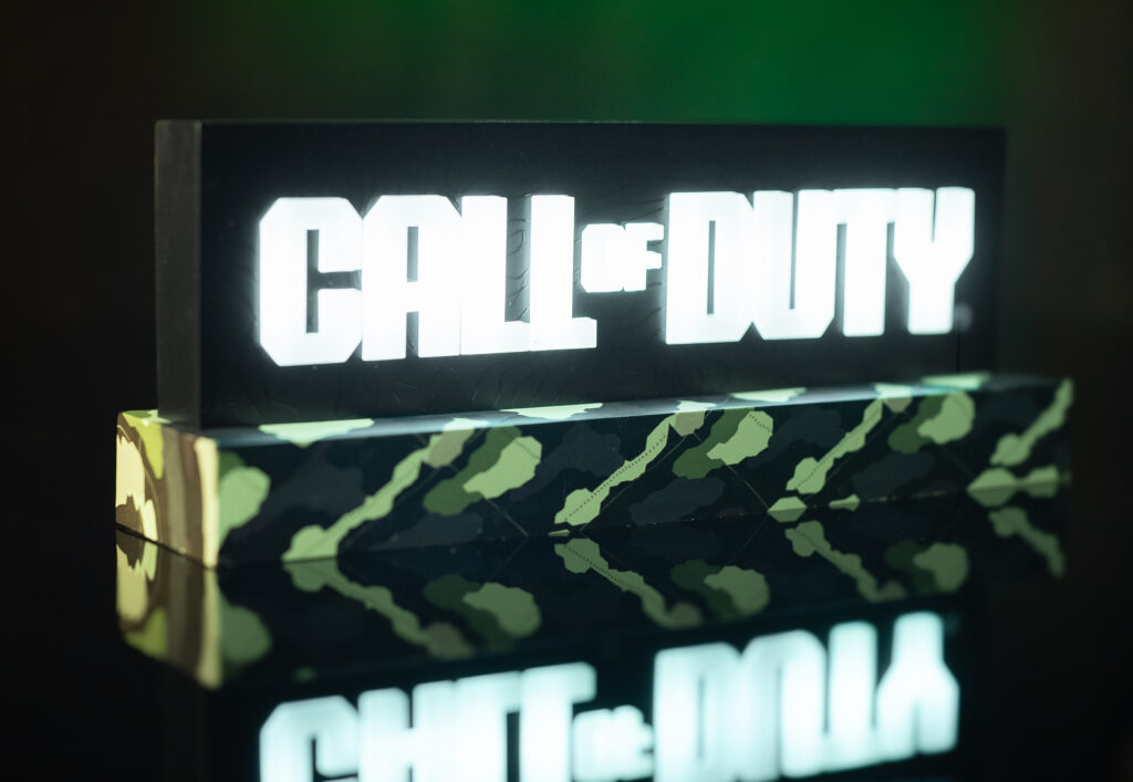 Lampe de bureau avec le logo Call of Duty allumé qui se reflète sur le bureau.